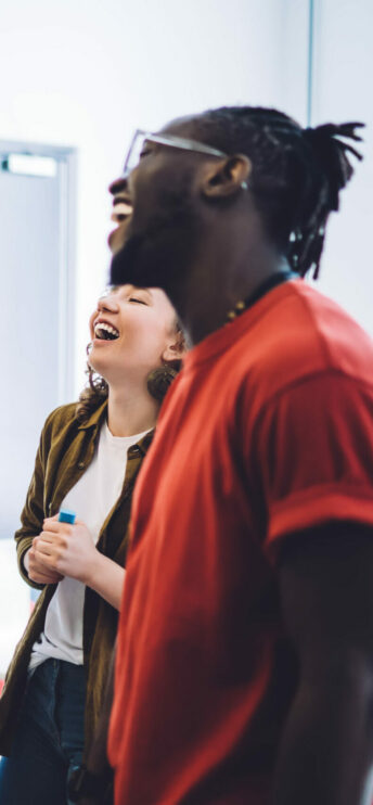 Une jeune femme et un jeune homme souriants au tableau de la classe en train de suivre une formation disc